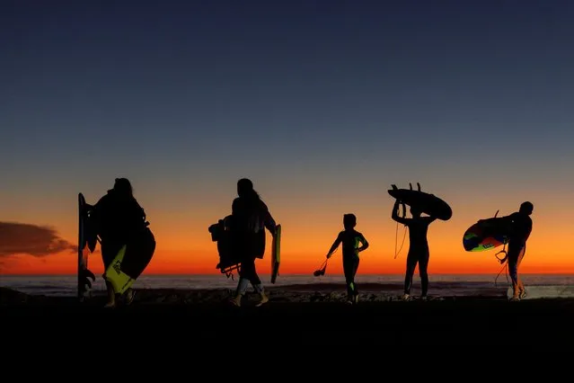 A family makes their way to their vehicle as they leave the beach after sunset in Encinitas, California, U.S., January 11, 2022. (Photo by Mike Blake/Reuters)