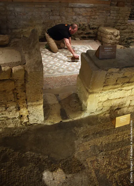 David Rawcliffe, house and monument steward at the National Trust's Chedworth Roman Villa cleans a Roman mosiac in the new environmentally-controlled conservation shelter near Cirencester, England
