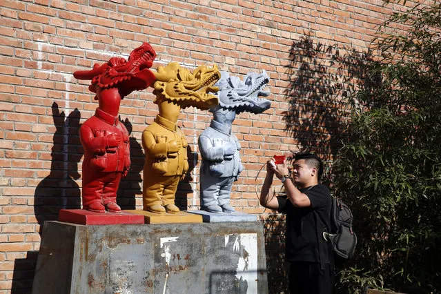 A man takes a photo of an art work displayed at the 798 art district in Beijing Tuesday, May 23, 2017. Started as a artist commune, the area quickly became popular with tourists and locals seeking a break from the more traditional sights in the Chinese capital. (Photo by Ng Han Guan/AP Photo)