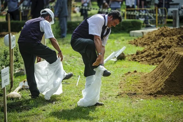 Gravediggers take off their disposable overalls during the first National Grave Digging competition at the public cemetery of Debrecen, 226 kms east of Budapest, Hungary, Friday, June 3, 2016. (Photo by Zsolt Czegledi/MTI via AP Photo)