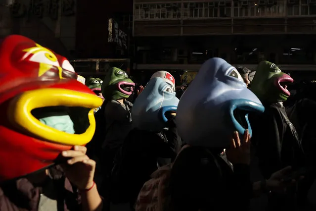 Pro-democracy protesters wearing frog shaped headgear march on a street in Hong Kong, Sunday, December 8, 2019. (Photo by Mark Schiefelbein/AP Photo)