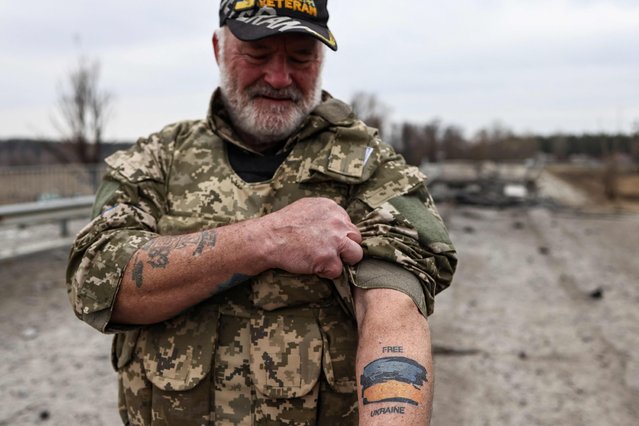 US war veteran Steven Straub shows his tatto with the Ukranian flag as they patrol on a road near Buda-Babynetska, north of Kyiv, on April 5, 2022, days after Russian forces retreated from the area. (Photo by Ronaldo Schemidt/AFP Photo)