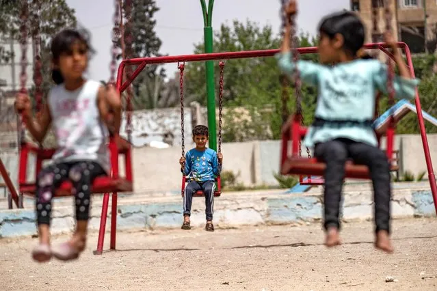 Syrian children play in a refurbished playground in the northern city of Raqa on April 30, 2022. (Photo by Delil Souleiman/AFP Photo)