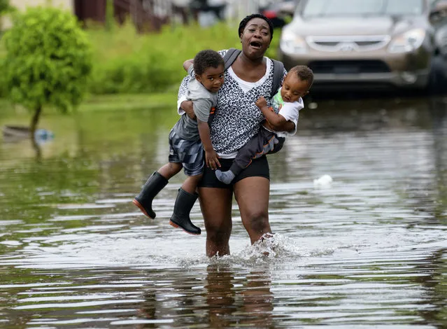Terrian Jones reacts as she feels something moving in the water at her feet as she carries Drew and Chance Furlough to their mother on Belfast Street in New Orleans during flooding from a storm in the Gulf Mexico that dumped lots of rain, July 10, 2019. (Photo by Matthew Hinton/AP Photo)