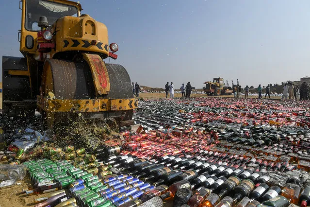 An official uses a steamroller to crush seized bottles of liquor, previously smuggled into the country, on the outskirts of Karachi on December 13, 2019. (Photo by Asif Hassan/AFP Photo)