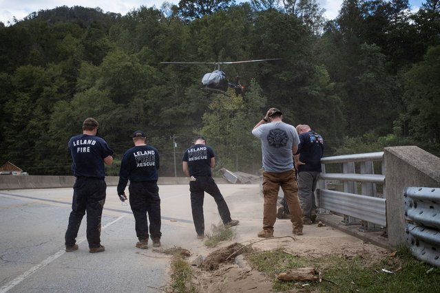 Fire and Rescue members stand as a helicopter takes off of a bridge, following the passing of Hurricane Helene, in Bat Cave, North Carolina, September 30, 2024. (Photo by Marco Bello/Reuters)