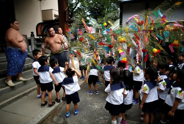 Tanabata festival decorations, made with a bamboo branch and strips of coloured paper, often with people's wishes written on them, are presented to sumo wrestlers from kindergarteners in Nagoya, Japan on July 18, 2017. (Photo by Issei Kato/Reuters)