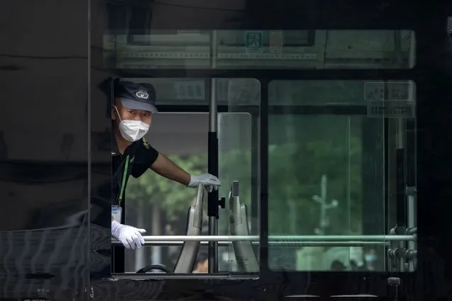 A security guard wearing a face mask looks out from the window of a public bus in Beijing, Friday, June 17, 2022. (Photo by Mark Schiefelbein/AP Photo)