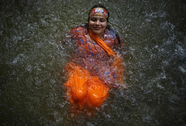 A Hindu devotee takes a dip at the Bagmati River as she participates in the “Bol Bom” (Say Shiva) pilgrimage in Kathmandu July 21, 2014. The faithful, chanting the name of Lord Shiva, run about 15 km (9 miles) barefooted toward Pashupatinath temple seeking good health, wealth and happiness. (Photo by Navesh Chitrakar/Reuters)
