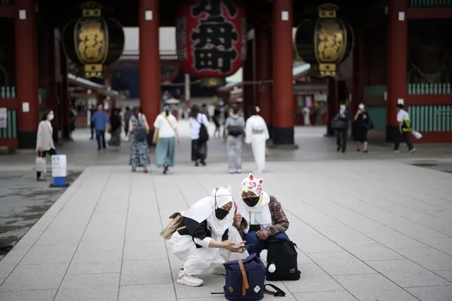 Foreign tourists wearing protective masks to help curb the spread of the coronavirus take a selfie at a shopping street at the Asakusa district Friday, June 10, 2022, in Tokyo. (Photo by Eugene Hoshiko/AP Photo)