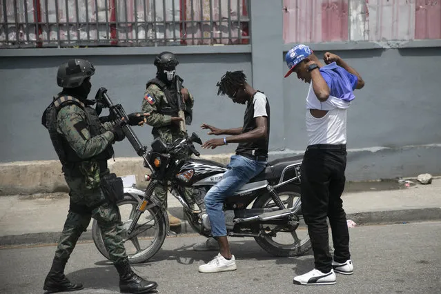 Armed forces check two men who were riding a motorcycle for weapons, at the area of ​​state offices of Port-au-Prince, Haiti, Monday, July 11, 2022. Radio TV Caraibe, a popular radio station in Haiti announced on Monday that it would stop broadcasting for one week to protest widespread violence in the capital. (Photo by Joseph Odelyn/AP Photo)