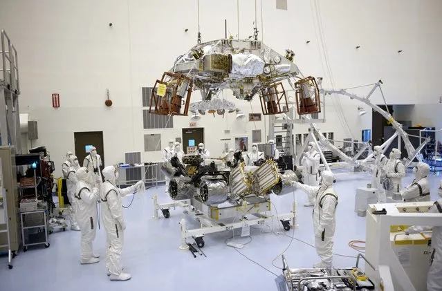 Preparing for integration to the rover Curiosity, technicians help guide the rocket-powered descent stage over the rover at NASA's Kennedy Space Center Payload Hazardous Servicing Facility, on September 23, 2011. (Photo by Kim Shiflett/NASA)