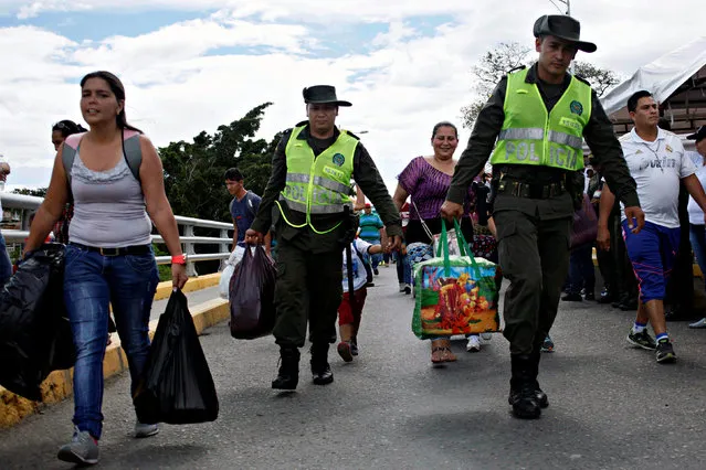Colombian police officers help people to carry bags as they cross the Colombian-Venezuelan border over the Simon Bolivar international bridge after shopping in Cucuta, Colombia, July 17, 2016. (Photo by Carlos Eduardo Ramirez/Reuters)