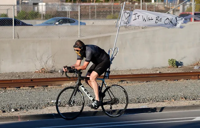 A banner reading “It Will Be Ok” waves from the bicycle of a man wearing a mask as he cycles through the streets of Oakland, California, USA, 30 March 2020. California Governor Gavin Newsom enforced a state-wide shelter-in-place legal order directing their residents to stay at home, except for essential work and essential needs such as grocery shopping, amid the ongoing coronavirus pandemic. (Photo by John G. Mabanglo/EPA/EFE)