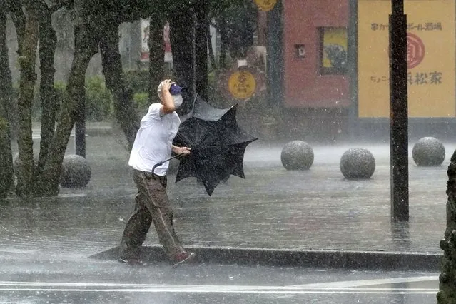 A man is drenched by the rain brought by Tropical Storm Meari, in Hamamatsu, Shizuoka prefecture, central Japan Saturday, August 13, 2022. The storm unleashed heavy rains on Japan's main Honshu island as it headed northward Saturday toward the capital, Tokyo, according to Japanese weather officials. (Photo by Kyodo News via AP Photo)