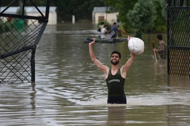 An Indian policeman holds his weapon while negotiating flood waters in the outskirts of Srinagar on September 4, 2014. Flooding has hit hundreds of villages across the picturesque Kashmir Valley in the country's north, leaving at least 16 people dead, and forcing the closure of schools and some roads, authorities said. (Photo by Tauseef Mustafa/AFP Photo)
