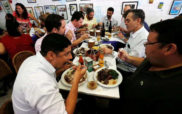 People enjoy the Brazilian traditional dish called feijoada (black bean and meat stew) at the Bar do Mineiro in Rio de Janeiro, Brazil, March 24, 2016. (Photo by Sergio Moraes/Reuters)