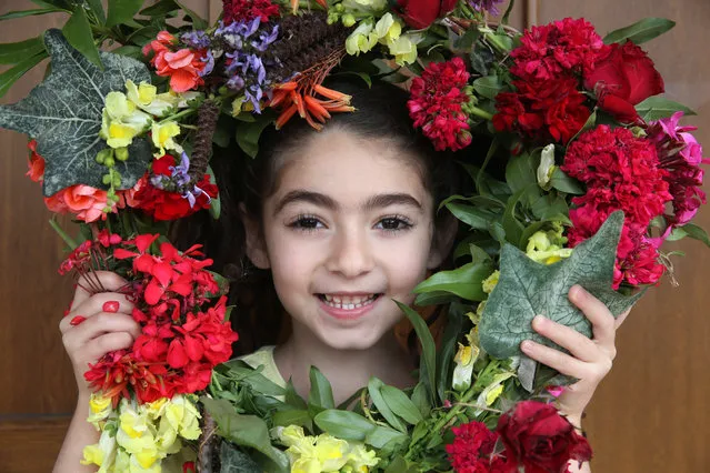 A little girl poses holding a decorated magical wreath of flowers collected from the garden of her home to celebrate May Day, Ko​rnos village, Cyprus 01 May 2020. (Photo by Katia Christodoulou/EPA/EFE)