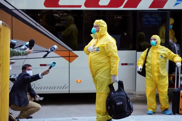 A crew member of the Australian cruise ship Greg Mortimer, dressed in protective gear as a preventive measure against the spread of the new coronavirus, speaks to reporters after arriving at a hotel in Montevideo, Uruguay, Tuesday, May 12, 2020. Crew members disembarked the new coronavirus-stricken cruise ship Tuesday, anchored off Uruguay's coast since March 27, after the Uruguayan government decided to transfer them to hotels to carry out their quarantine. (Photo by Matilde Campodonico/AP Photo)