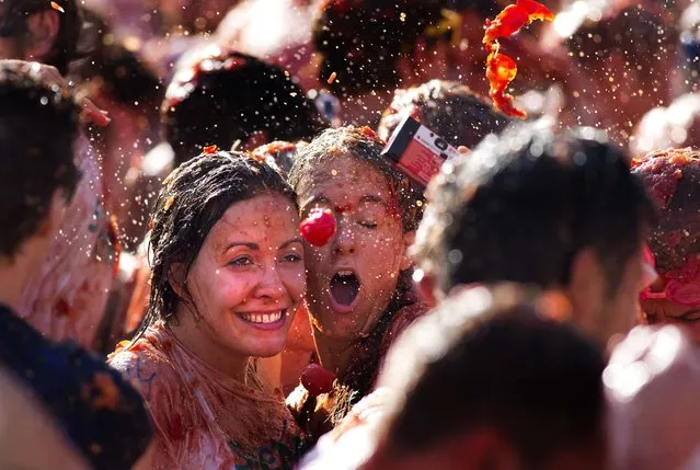 A tomato is about to hit two women taking a selfie during a tomato fight in front of the Royal Palace turning Amsterdam's central Dam square into a red pulpy mess Sunday, September 14, 2014. Entrepreneurs have seized upon Russia's boycott of European produce to set up a tomato-throwing fight. (Photo by Peter Dejong/AP Photo)