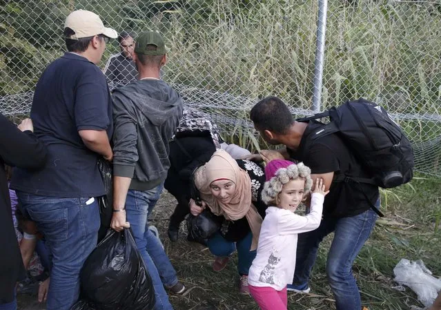 Migrants pass under highway security fence as they try to find a new way to enter Hungary after Hungarian police sealed the border with Serbia near the village of Horgos, Serbia, September 14, 2015, near the Hungarian migrant collection point in Roszke. (Photo by Marko Djurica/Reuters)