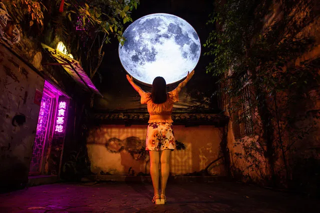 A visitor poses for a photo in front of a giant full moon installation at Kwai Chai Hong, a heritage revival back alley in Chinatown on September 03, 2022 in Kuala Lumpur, Malaysia. The Mid-Autumn Festival is held on the fifteenth day of the eighth month (September 10 this year) in the Chinese lunar calendar, on a full moon day. The festival is a joyous celebration with family reunions, eating mooncakes, street decorations and children holding lanterns as they march around the neighbourhood at night. (Photo by Annice Lyn/Getty Images)