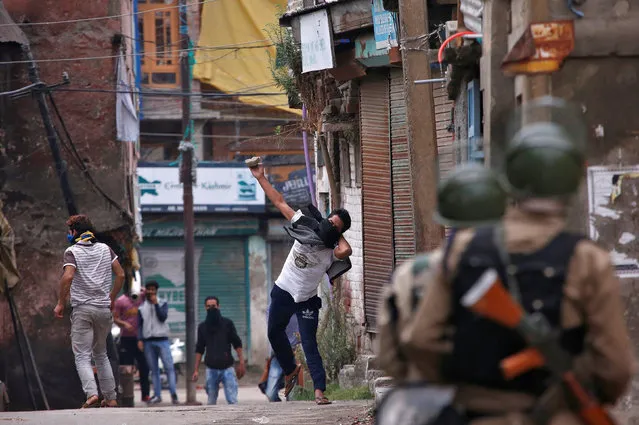 A protester throws a stone towards Indian policemen during a protest in Srinagar against the recent killings in Kashmir, August 29, 2016. (Photo by Danish Ismail/Reuters)