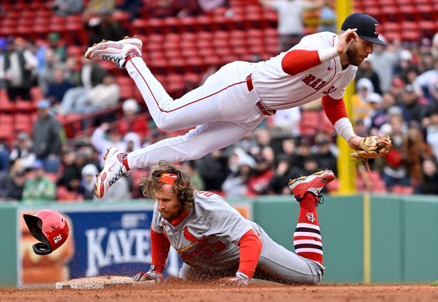Boston Red Sox shortstop Trevor Story (10) leaps out of the way as St. Louis Cardinals infield Brendan Donovan (33) continues to slide into second base during the ninth inning at Fenway Park in Boston, Massachusetts on April 6, 2025. (Photo by Eric Canha/Reuters)