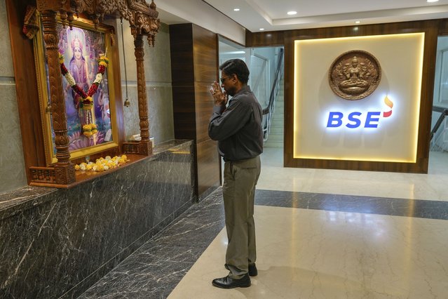 A person working in the Bombay Stock Exchange building prays to Hindu Goddess Laxmi, the embodiment of wealth, fortune, prosperity, before starting his work in Mumbai, India, Tuesday, April 8, 2025. (Photo by Rafiq Maqbool/AP Photo)