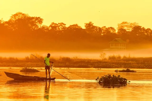 A man fishes at Maguri Motapung Beel wetland during sunset in Tinsukia district in Assam on December 1, 2022. (Photo by Biju Boro/AFP Photo)