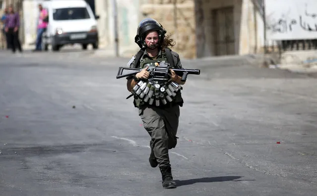 An Israeli border policewoman runs during clashes with Palestinian protesters following the killing of an Israeli couple, in the West Bank city of Hebron, October 2, 2015. An Israeli couple was killed Oct. 2 in front of their four children in an attack on the West Bank allegedly carried out by a Palestinian. The Islamic Hamas movement hailed the attack, which took place near the northern West Bank city of Nablus, as a "natural response to Israeli crimes". (Photo by Abed Al Hashlamoun/EPA)