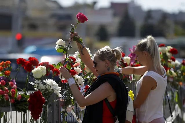 People lay flowers at the place where a protester died amid the clashes, in Minsk, Belarus, Tuesday, August  11, 2020. Thousands of opposition supporters who also protested the results met with a tough police crackdown in Minsk and several other Belarusian cities for two straight nights. Belarus' health officials said over 200 people have been hospitalized with injuries following the protests, and some underwent surgery. (Photo by Sergei Grits/AP Photo)