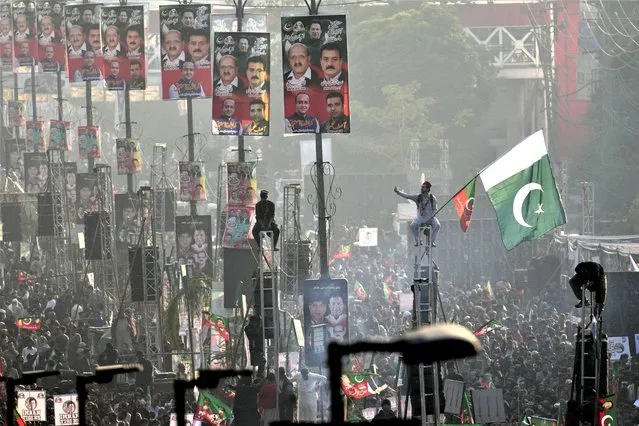 Supporters of Pakistan's former Prime Minister Imran Khan's 'Pakistan Tehreek-e-Insaf' party climb on poles while they participate in a rally, in Rawalpindi, Pakistan, Saturday, November 26, 2022. Khan said Saturday his party was quitting the country's regional and national assemblies, as he made his first public appearance since being wounded in a gun attack earlier this month. (Photo by Anjum Naveed/AP Photo)