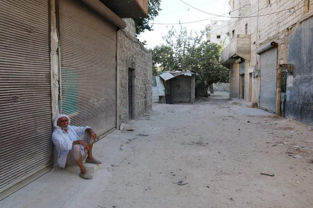 A man sits in front of closed shops in the rebel-held al-Sheikh Said neighbourhood of Aleppo, Syria September 1, 2016. (Photo by Abdalrhman Ismail/Reuters)