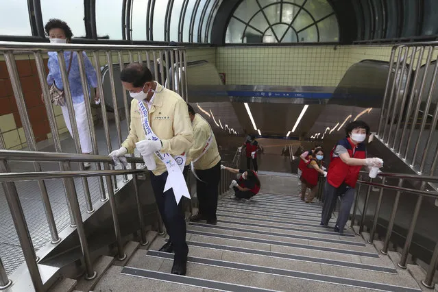 Government officials and volunteers disinfect as a precaution against the coronavirus at a subway station entrance in Goyang, South Korea, Tuesday, August 25, 2020. (Photo by Ahn Young-joon/AP Photo)