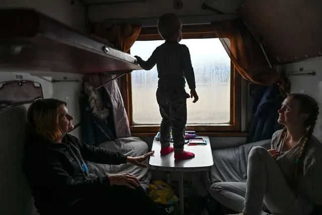 Young boy Dima plays with his mother Aleksya (R) and auntie Svetlana (L) inside an evacuation train from Kherson to Khmelnytskyi at Kherson station, on Sunday, December 18, 2022. Five weeks after liberation, the city of Kherson and the surrounding villages are bombarded daily by Russian troops from the left bank of the Dnieper. More and more innocent people are dying and become injured. Many homes and local infrastructure are also damaged or destroyed. For the past three weeks, a special humanitarian train has been available to assist in the evacuation of civilians leaving the city. The destination city after more than 15 hours of travel is Khmelnytskyi, located in western Ukraine. On Monday, December 12, 2022, in Khmelnytskyi, Khmelnytskyi Oblast, Ukraine. (Photo by Artur Widak/NurPhoto via Getty Images)