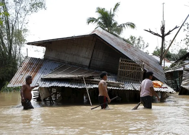 Residents wade in floodwaters past a house damaged at the height of Typhoon Koppu in Jaen, Nueva Ecija in northern Philippines October 20, 2015. (Photo by Erik De Castro/Reuters)