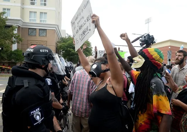 Protesters confront a line of police outside Bank of America Stadium in Charlotte, N.C., Sunday, September 25, 2016. The Carolina Panthers hosted an NFL football game with the Minnesota Vikings at the stadium. When the national anthem was played, the protesters all dropped to one knee as many NFL players have been doing for weeks to call attention to issues, including police shootings. (Photo by Diedra Laird/The Charlotte Observer via AP Photo)