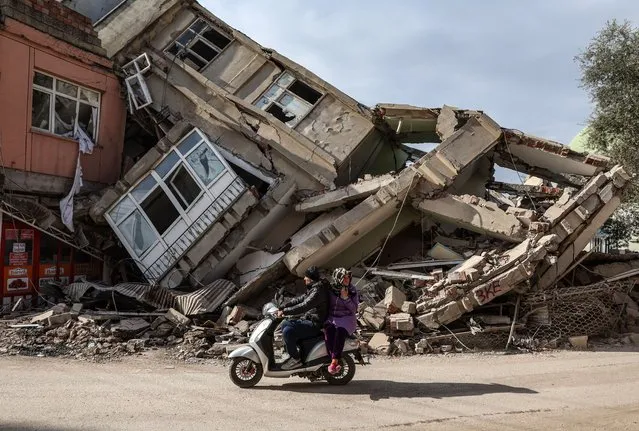 People ride a scooter in front of a collapsed building after powerful earthquake in Adiyaman, Turkey, 19 February 2023. More than 45,000 people have died and thousands more are injured after two major earthquakes struck southern Turkey and northern Syria on 06 February. Authorities fear the death toll will keep climbing as rescuers look for survivors across the region. (Photo by Erdem Sahin/EPA)