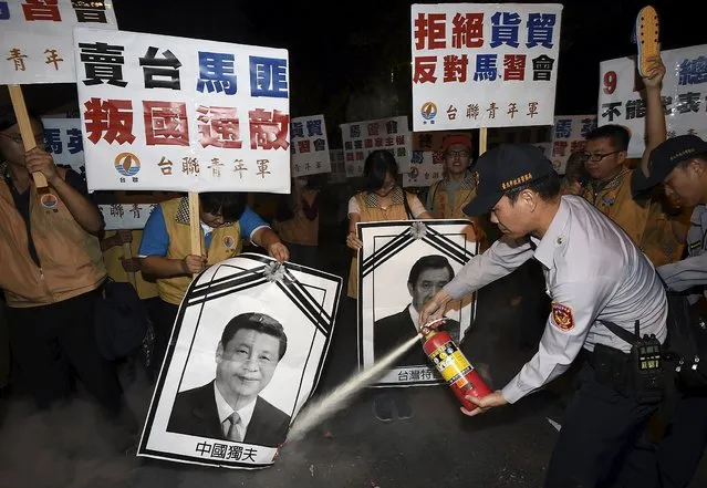 A police officer puts out fire on the portraits of Chinese President Xi Jinping and Taiwan's President Ma Ying-jeou (R) during a protest against the upcoming Singapore meeting between Ma and Xi, outside Taipei Songshan airport, November 7, 2015. Leaders of political rivals Taiwan and China meet for the first time in more than 60 years on Saturday for talks that come amid rising anti-Chinese sentiment on the self-ruled democratic island and weeks ahead of elections. (Photo by Reuters/Stringer)