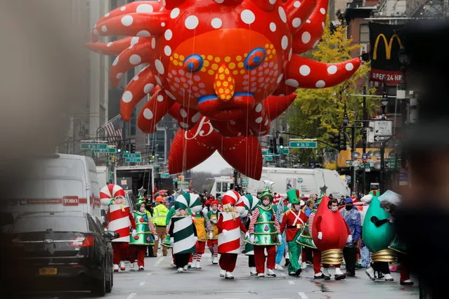 Assistants carry Yayoi Kusama's “Love Flies Up to the Sky” balloon during the 94th Macy's Thanksgiving Day Parade closed to the spectators due to the spread of the coronavirus disease (COVID-19), in Manhattan, New York City, U.S., November 26, 2020. (Photo by Andrew Kelly/Reuters)