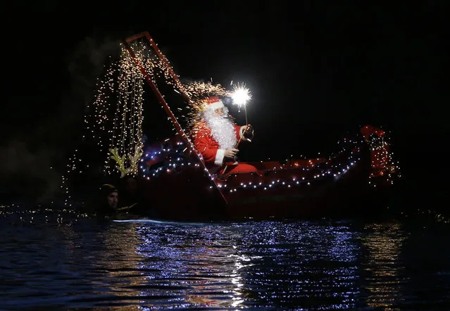 A man dressed as Santa Claus lights flares as he sits on a boat in Imperia, near Genoa, Italy, Wednesday, December 24, 2014. (Photo by Antonio Calanni/AP Photo)