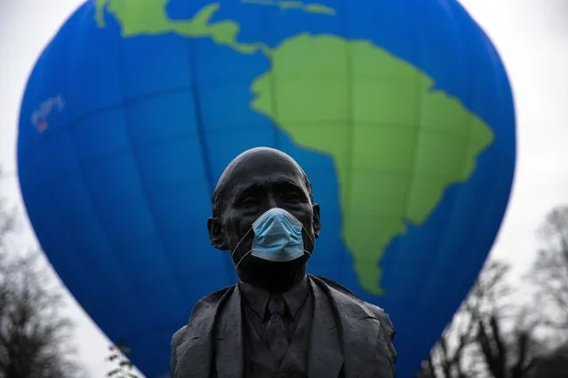 The bust of French statesman Robert Schuman, one of the founders of the European Union, is seen while environmental activists launch a hot air balloon during a demonstration outside of an EU summit in Brussels, Thursday, December 10, 2020. European Union leaders meet for a year-end summit that will address anything from climate, sanctions against Turkey to budget and virus recovery plans. Brexit will be discussed on the sidelines. (Photo by Francisco Seco/AP Photo)