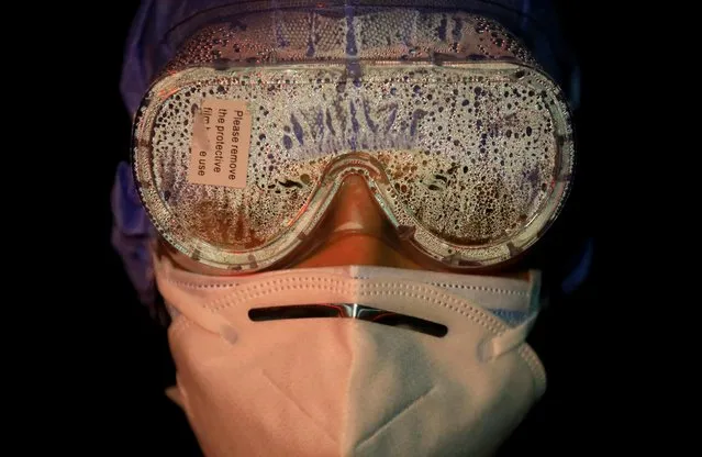 A female soldier's goggles are covered with vapor after handling bodies of coronavirus victims in Kathmandu, Nepal, November 11, 2020. Nepal Army spokesman Shantosh B. Poudyal said the 95,000-strong force was putting women soldiers in new roles, part of a programme to empower them. “Women were deployed in combat duty, hospitals, ordnance, engineers and disasters before. This is the first time they are managing the bodies from hospitals and transporting them to the crematorium”, Poudyal told Reuters. “You can say it is breaking the borders ... breaking the glass ceiling”. Nepal's army is responsible for managing the bodies of coronavirus victims across the nation. (Photo by Navesh Chitrakar/Reuters)