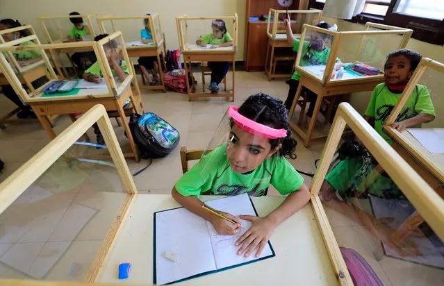 Students listen to a teacher while sitting behind glass dividers on their desks in a classroom at Tiba Maadi School, following months of closure due to the coronavirus disease (COVID-19) outbreak, in the Cairo suburb of Maadi, Egypt on November 1, 2020. (Photo by Amr Abdallah Dalsh/Reuters)