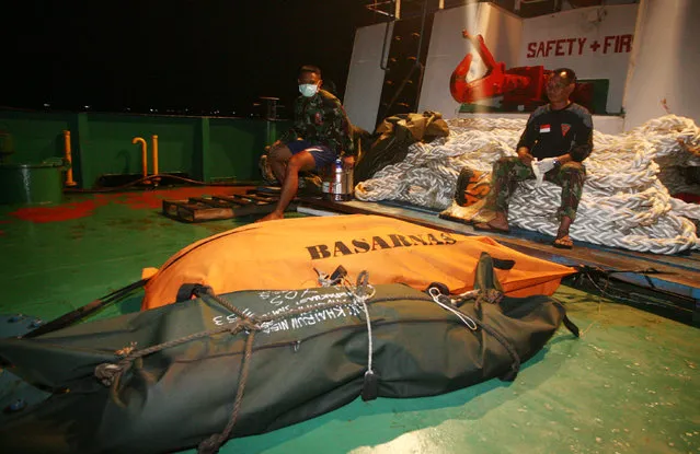 Indonesian soldiers  sit near  bodies of the victims of AirAsia flight QZ 8501 on a ship deployed on search operation in Kumai Gulf , Indonesia, Wednesday, December 31, 2014. (Photo by AP Photo/Media Indonesia/Susanto)