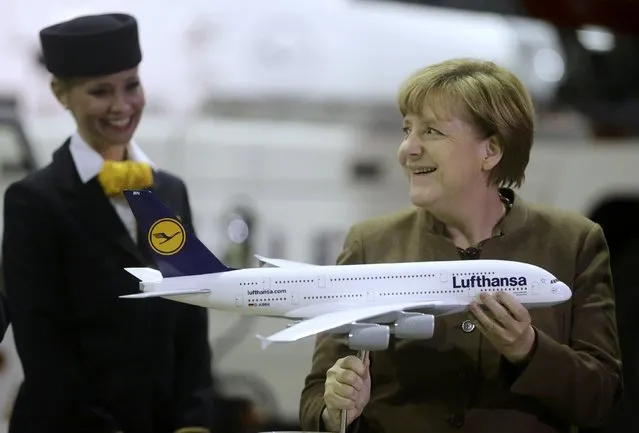 German Chancellor Angela Merkel smiles after receiving a model of the A300-800 'Deutschland' airplane during an aircraft christening ceremony at the Lufthansa Technik facility in Frankfurt, Germany November 18, 2015. (Photo by Kai Pfaffenbach/Reuters)