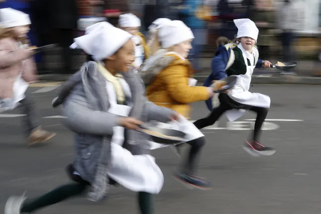 Schoolchildren from local schools take part in the children's races prior to the annual Pancake race in Olney, Buckinghamshire, England, Tuesday, February 25, 2020. Every year women clad in aprons and head scarves from Olney and the city of Liberal, in Kansas, USA, run their respective legs of the race with pancakes in their pans. According to legend, the Olney race started in 1445 when a harried housewife arrived at church on Shrove Tuesday still clutching her frying pan with a pancake in it. (Photo by Alastair Grant/AP Photo)