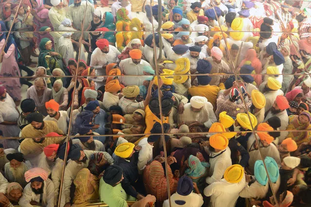 The reflection on the ceiling shows Indian Sikh devotees gathering to pay respects as a “Jalau” ritual takes place inside the Sikh Shrine Golden Temple in Amritsar on October 17, 2016. The “Jalau” took place on the occasion of the birth anniversary of the fourth Sikh Guru Ramdass, who was born in Lahore in 1574, and was the guru who established the city of Amritsar. (Photo by Narinder Nanu/AFP Photo)