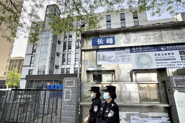 Police officers patrol past a barricaded building following a fire at a hospital in Beijing, Wednesday, April 19, 2023. More than a dozen people have died in a fire at the Beijing hospital that forced the evacuation of dozens of patients on Tuesday, Chinese state media reported. (Photo by Andy Wong/AP Photo)